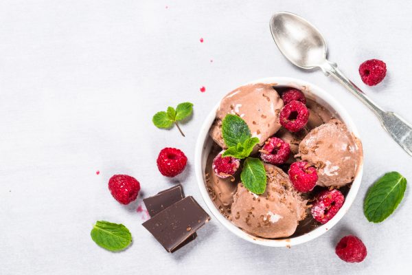Chocolate ice cream with raspberries. Top view on light stone table.